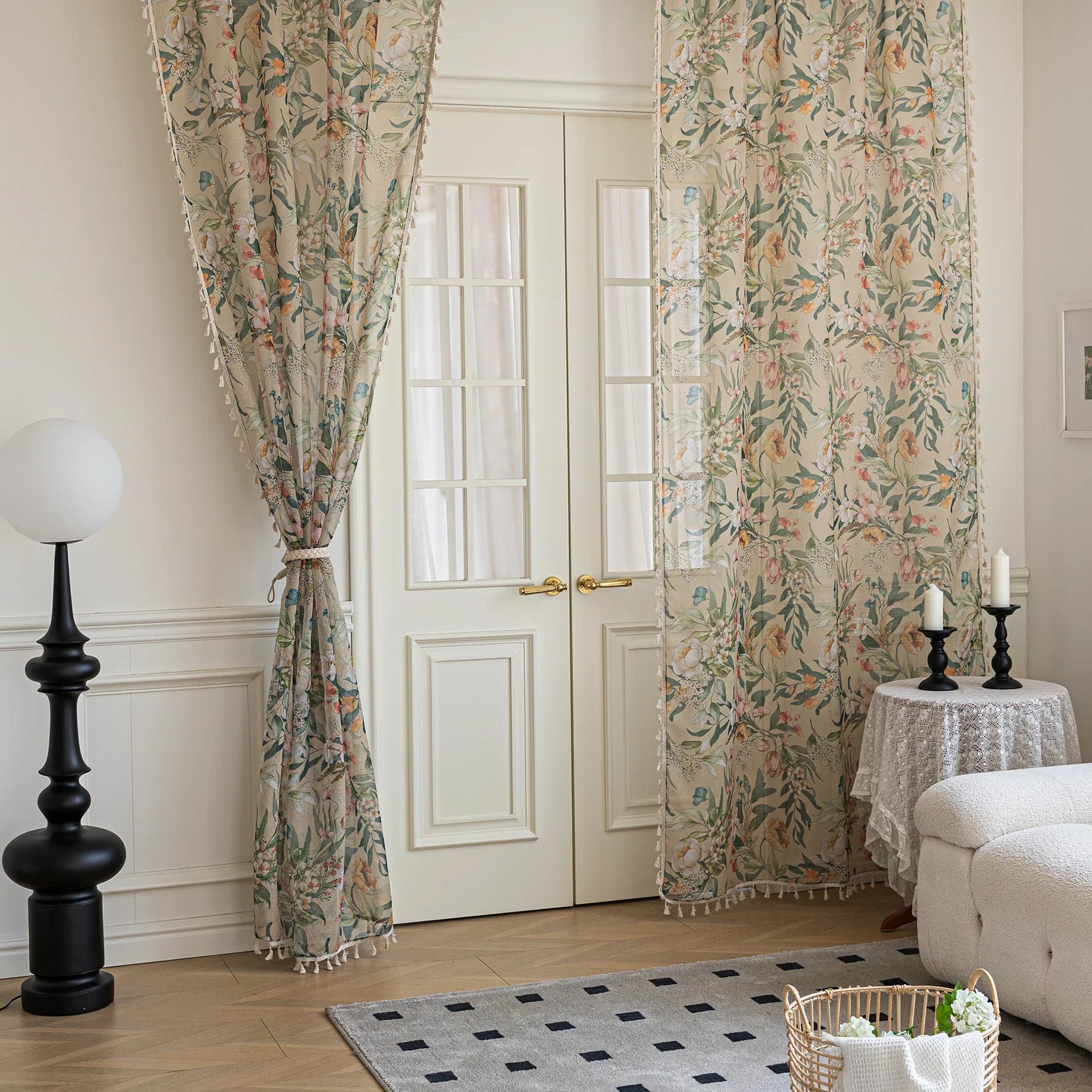 Close-up of beige sheer curtain with colorful floral and leafy pattern, decorated with delicate tassel trim, creating an elegant and airy botanical look for home interiors.
