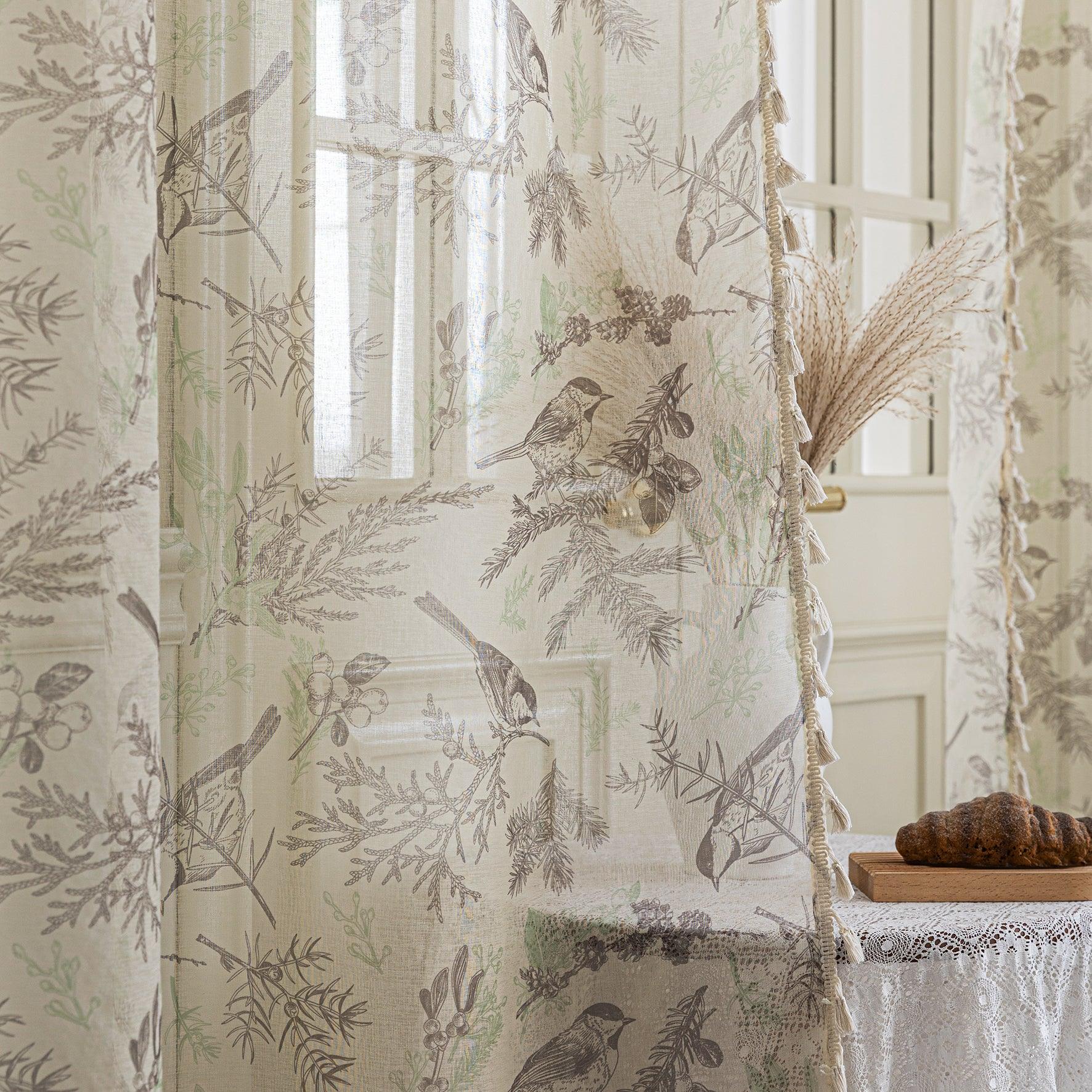 Beige linen curtain fabric with brown and green botanical and bird print, featuring decorative tassel trim.