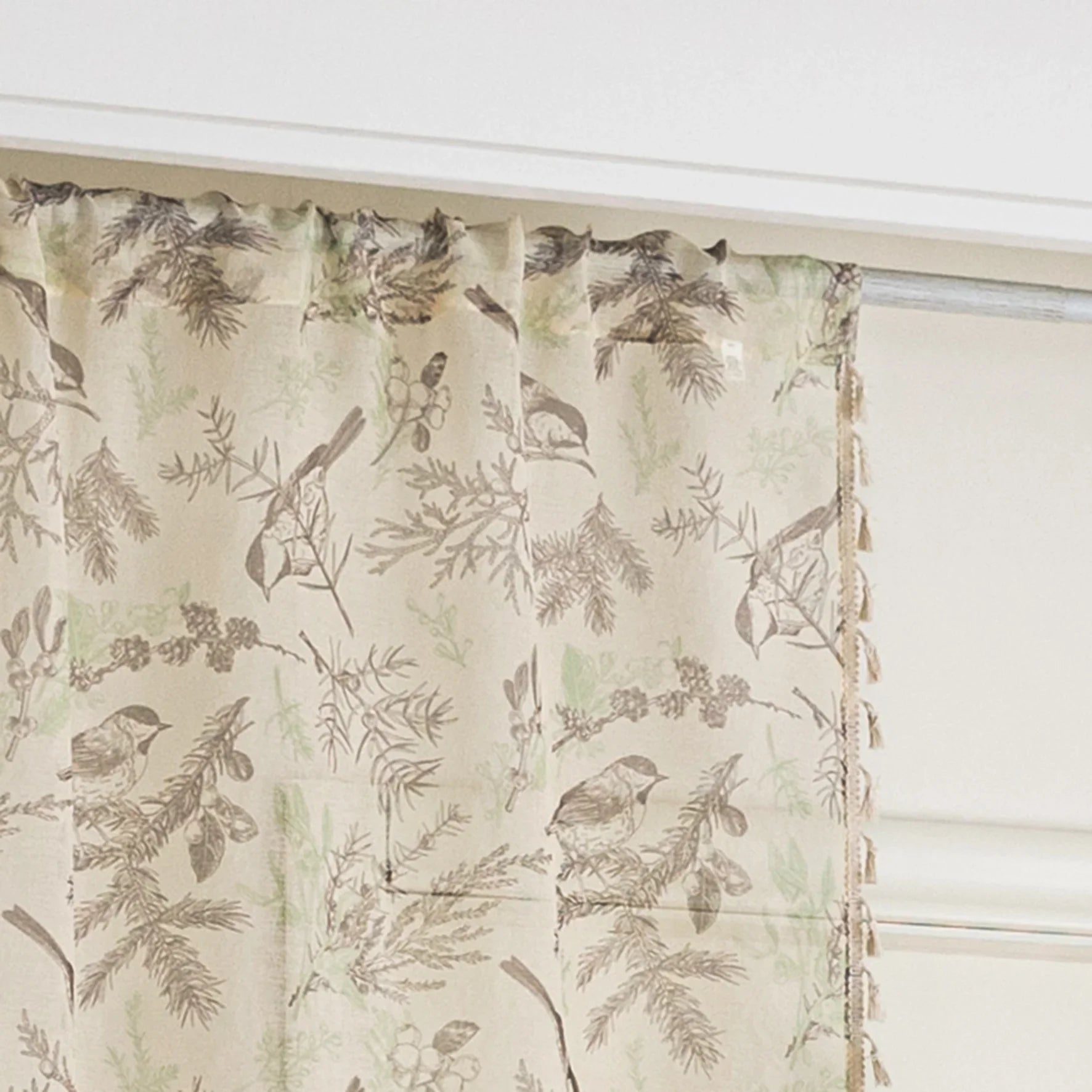 beige linen curtain fabric with brown and green botanical and bird print, featuring decorative tassel trim