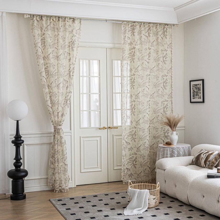 beige linen curtain fabric with brown and green botanical and bird print, featuring decorative tassel trim