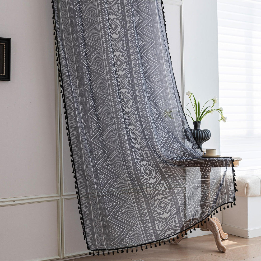Modern Black and White Geometric Sheer Curtains – Enhance your home with these contemporary sheer curtains featuring an intricate tribal-inspired geometric pattern in black and white. The lightweight fabric allows natural light to filter through while maintaining a sense of privacy, making them perfect for living rooms, bedrooms, or minimalist interiors. Finished with delicate black tassels along the edges, these curtains add a stylish yet subtle decorative touch that complements modern, boho, or Scandinavi