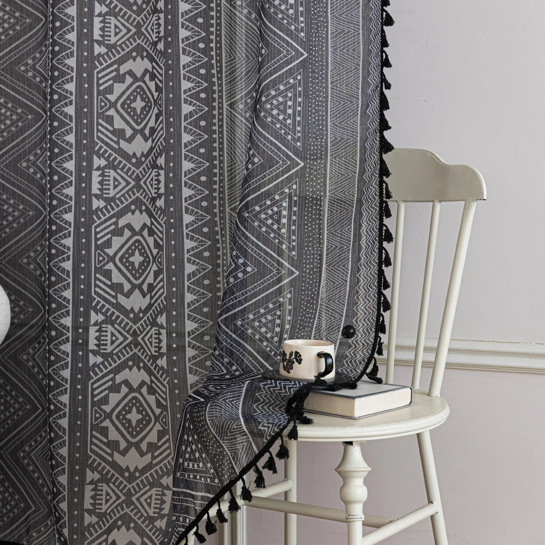 Modern Black and White Geometric Sheer Curtains – Enhance your home with these contemporary sheer curtains featuring an intricate tribal-inspired geometric pattern in black and white. The lightweight fabric allows natural light to filter through while maintaining a sense of privacy, making them perfect for living rooms, bedrooms, or minimalist interiors. Finished with delicate black tassels along the edges, these curtains add a stylish yet subtle decorative touch that complements modern, boho, or Scandinavi