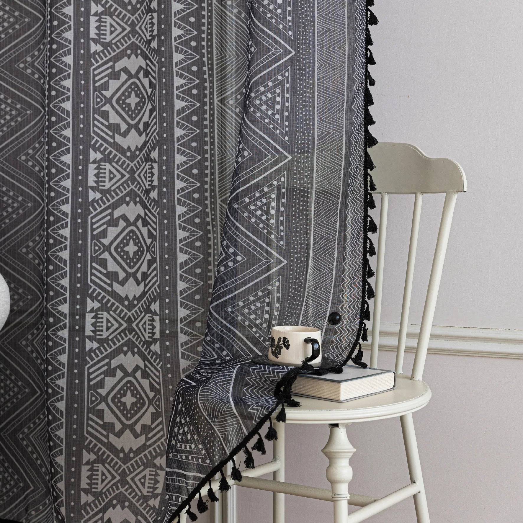 Modern Black and White Geometric Sheer Curtains – Enhance your home with these contemporary sheer curtains featuring an intricate tribal-inspired geometric pattern in black and white. The lightweight fabric allows natural light to filter through while maintaining a sense of privacy, making them perfect for living rooms, bedrooms, or minimalist interiors. Finished with delicate black tassels along the edges, these curtains add a stylish yet subtle decorative touch that complements modern, boho, or Scandinavi