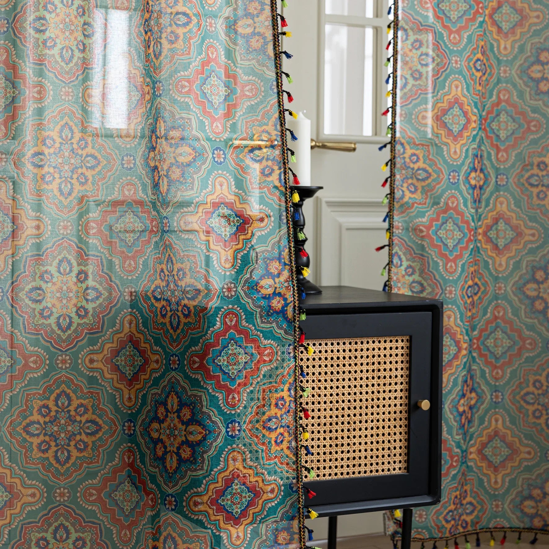 Bring vibrant elegance to your home with this bohemian-style sheer curtain, featuring an intricate geometric pattern in rich teal, orange, and gold tones. Crafted from lightweight, breathable fabric, it allows natural light to filter through while maintaining privacy. Perfect for living rooms, bedrooms, or creative spaces, this decorative curtain adds warmth and personality to any interior. The colorful tassel trim enhances its artisanal charm, making it a versatile choice for both modern and eclectic home 