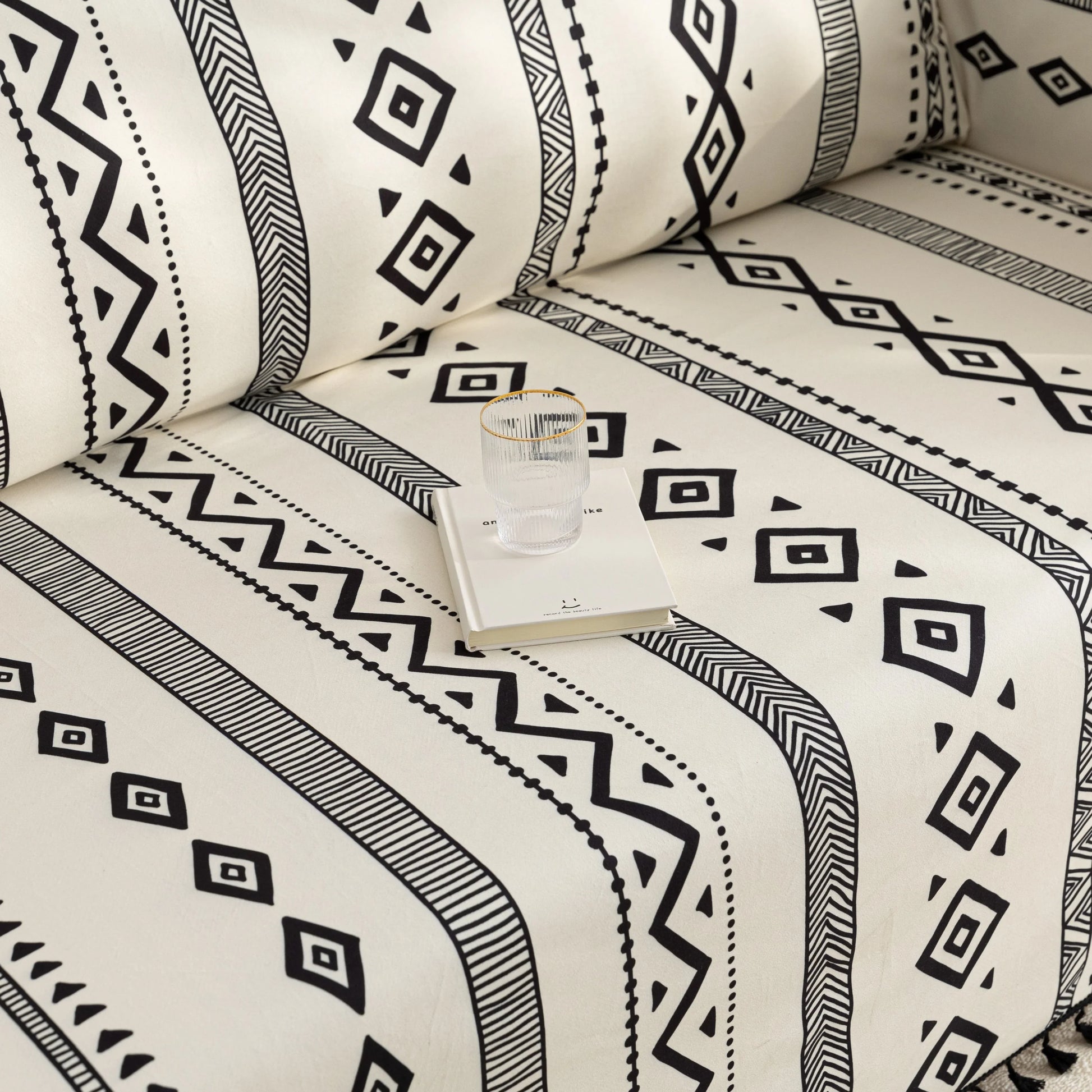 Modern black and white geometric patterned sofa cover with tribal-inspired diamond and stripe designs.