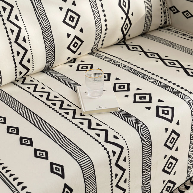 Modern black and white geometric patterned sofa cover with tribal-inspired diamond and stripe designs.