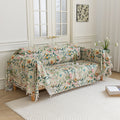 Beige floral sofa cover with vibrant botanical patterns in green, pink, yellow, and white, accented with delicate white tassel trim.