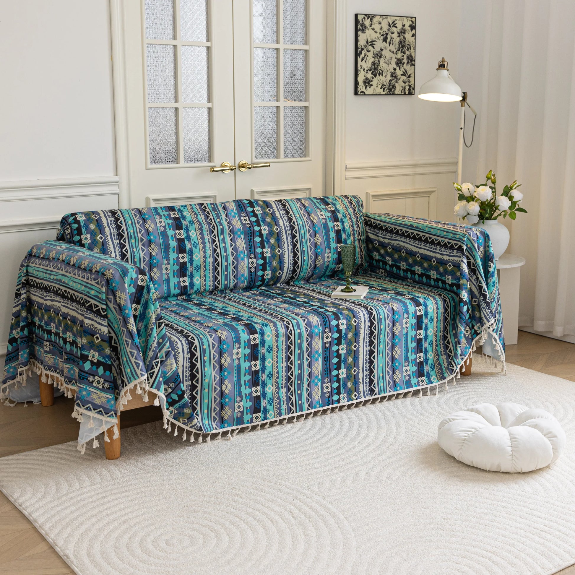 Bohemian-style sofa cover featuring vibrant blue, teal, and navy geometric tribal patterns with white tassel edging.