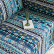 Bohemian-style sofa cover featuring vibrant blue, teal, and navy geometric tribal patterns with white tassel edging.