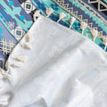 Bohemian-style sofa cover featuring vibrant blue, teal, and navy geometric tribal patterns with white tassel edging.