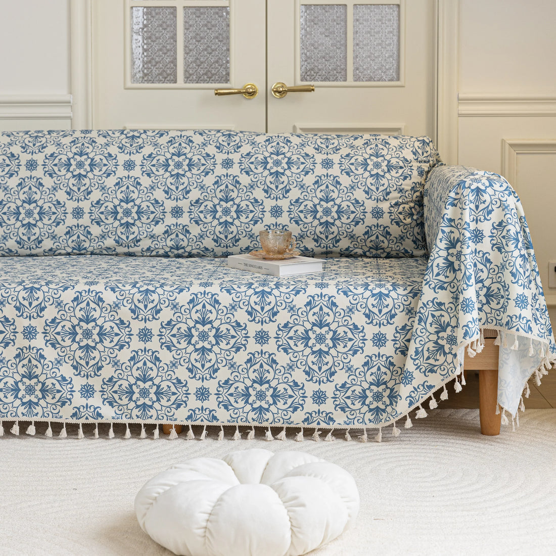 Elegant sofa cover with a blue floral damask pattern on a white background, finished with decorative white tassel fringe,