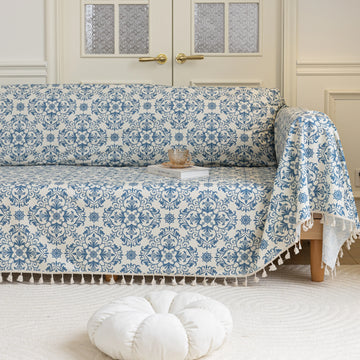 Elegant sofa cover with a blue floral damask pattern on a white background, finished with decorative white tassel fringe,