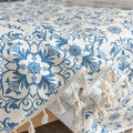 Elegant sofa cover with a blue floral damask pattern on a white background, finished with decorative white tassel fringe,