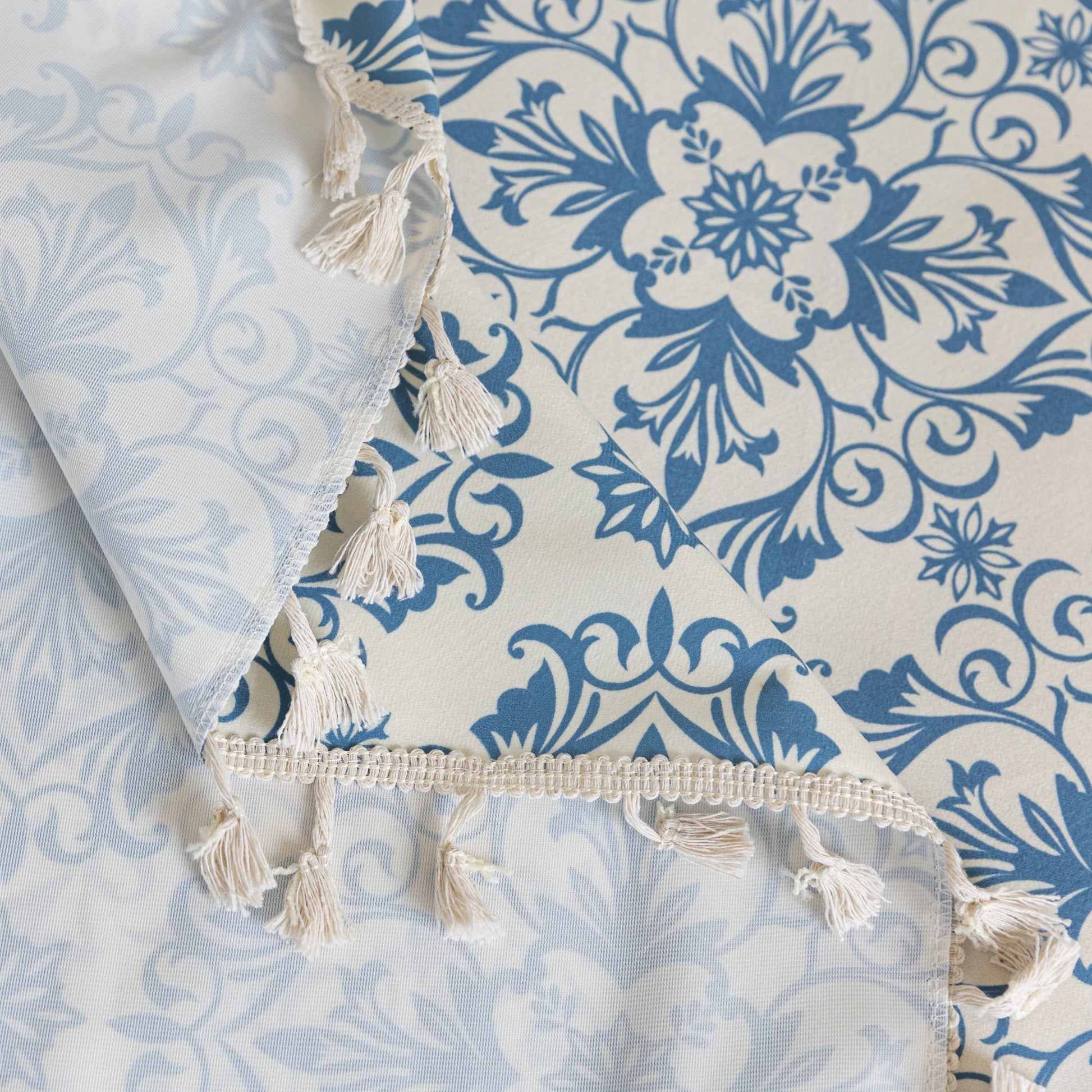 Elegant sofa cover with a blue floral damask pattern on a white background, finished with decorative white tassel fringe.
