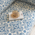 Elegant sofa cover with a blue floral damask pattern on a white background, finished with decorative white tassel fringe.