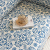 Elegant sofa cover with a blue floral damask pattern on a white background, finished with decorative white tassel fringe.