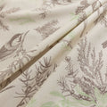 Beige sofa cover with delicate botanical and bird illustrations in brown and light green, featuring nature-inspired patterns.