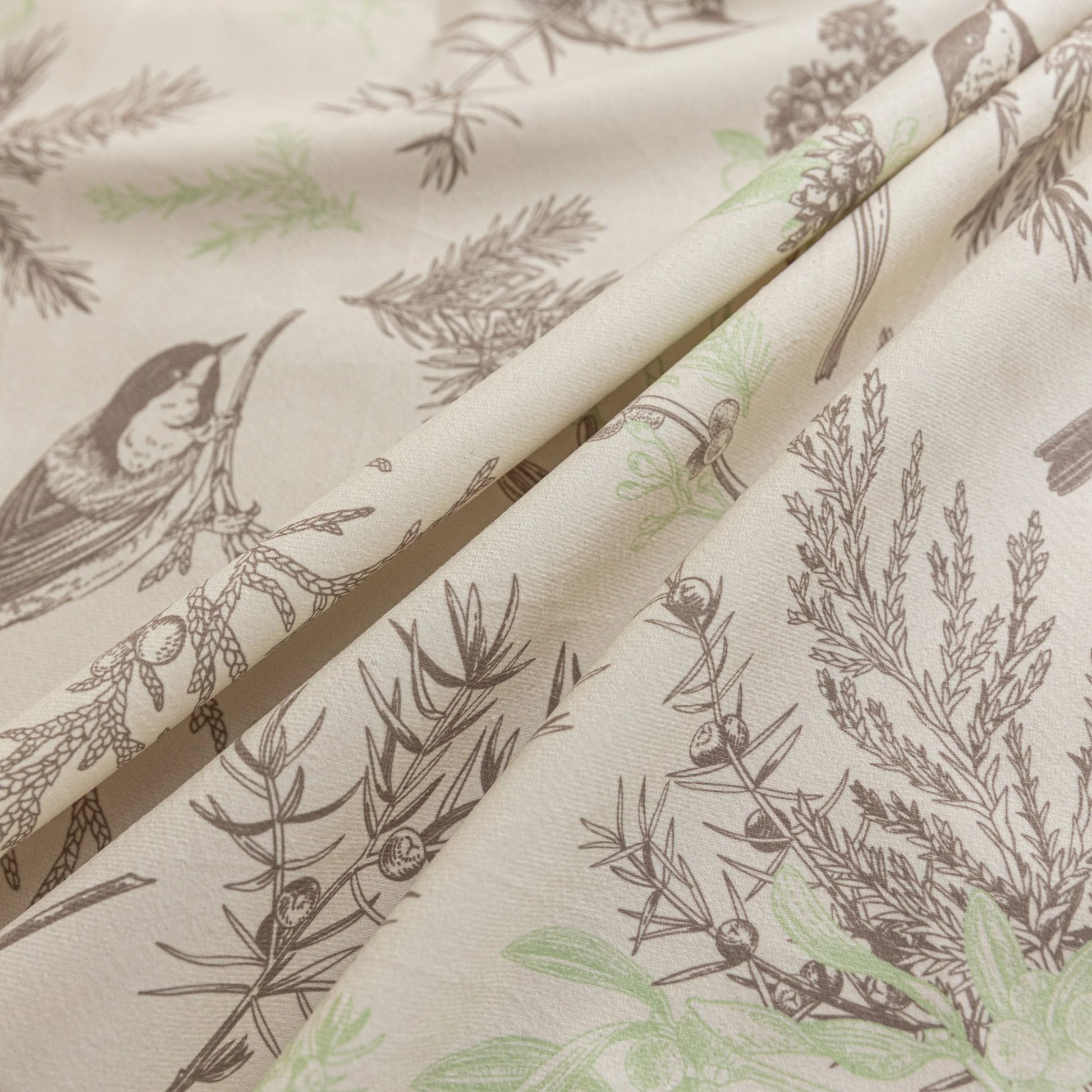 Beige sofa cover with delicate botanical and bird illustrations in brown and light green, featuring nature-inspired patterns.