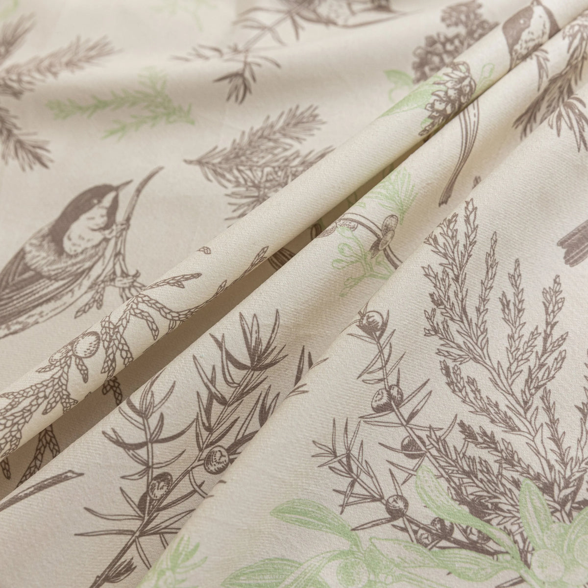 Beige sofa cover with delicate botanical and bird illustrations in brown and light green, featuring nature-inspired patterns.