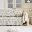 Beige sofa cover with delicate botanical and bird illustrations in brown and light green, featuring nature-inspired patterns