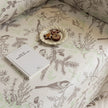 Beige sofa cover with delicate botanical and bird illustrations in brown and light green, featuring nature-inspired patterns