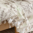 Beige sofa cover with delicate botanical and bird illustrations in brown and light green, featuring nature-inspired patterns.
