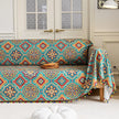 Colorful sofa cover with vibrant Moroccan-style geometric patterns in teal, red, yellow, and blue, finished with multicolor tassel trim.