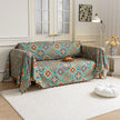 Colorful sofa cover with vibrant Moroccan-style geometric patterns in teal, red, yellow, and blue, finished with multicolor tassel trim.