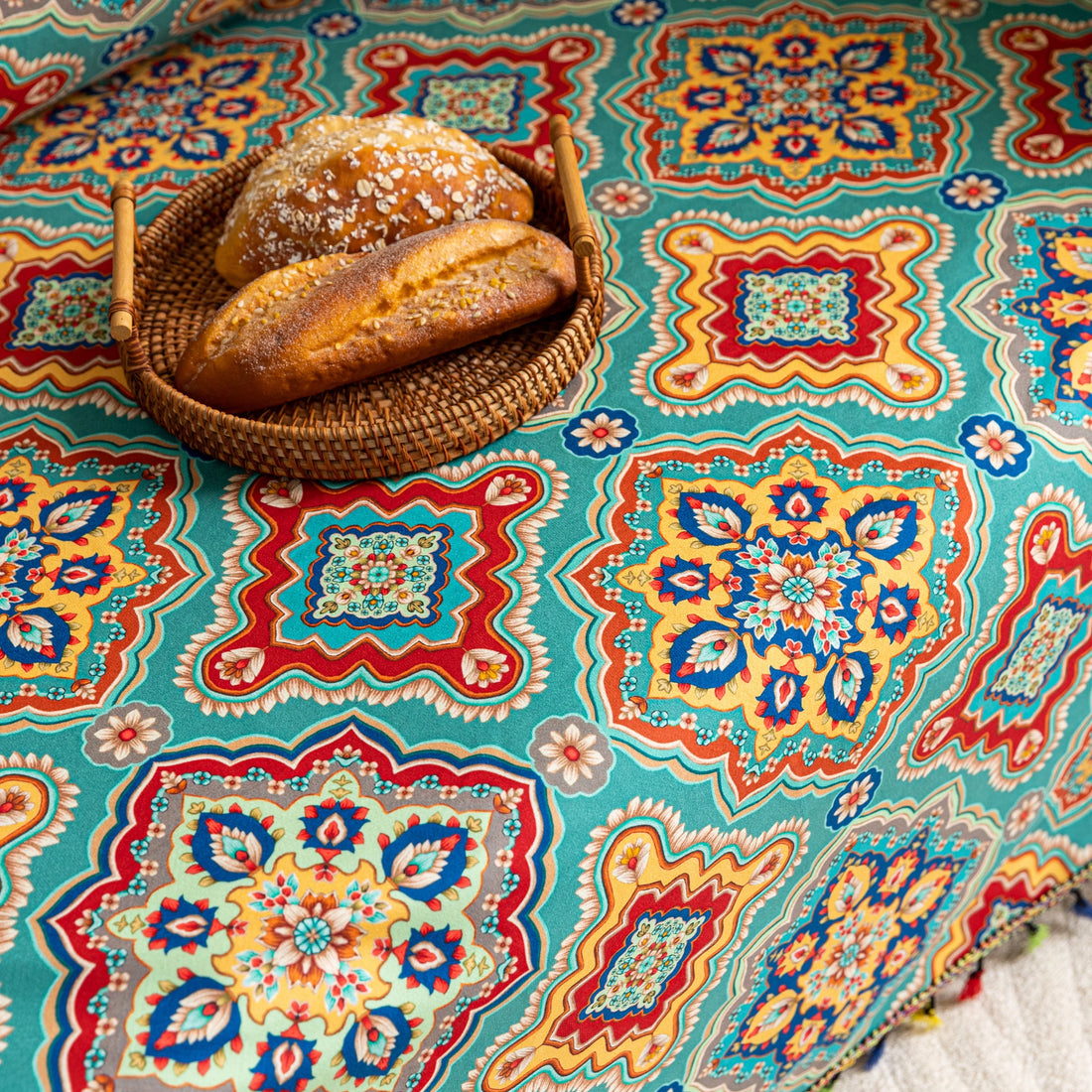 Colorful sofa cover with vibrant Moroccan-style geometric patterns in teal, red, yellow, and blue, finished with multicolor tassel trim.