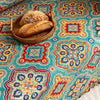 Colorful sofa cover with vibrant Moroccan-style geometric patterns in teal, red, yellow, and blue, finished with multicolor tassel trim.