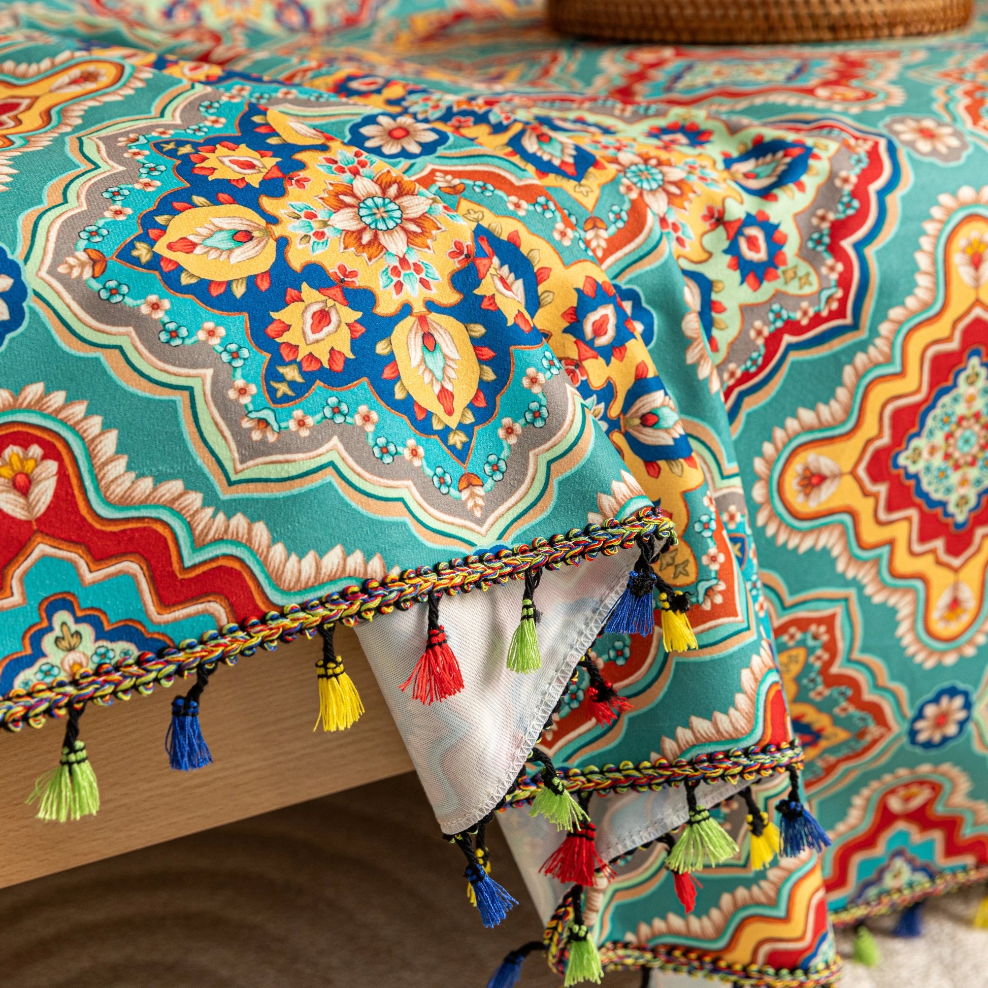 Colorful sofa cover with vibrant Moroccan-style geometric patterns in teal, red, yellow, and blue, finished with multicolor tassel trim.