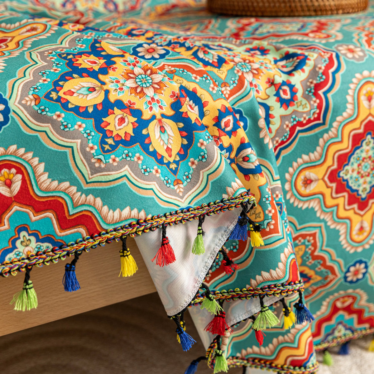 Colorful sofa cover with vibrant Moroccan-style geometric patterns in teal, red, yellow, and blue, finished with multicolor tassel trim.