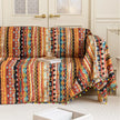 Southwestern-inspired sofa cover with vibrant tribal geometric patterns in red, orange, black, and turquoise, accented with colorful tassels.