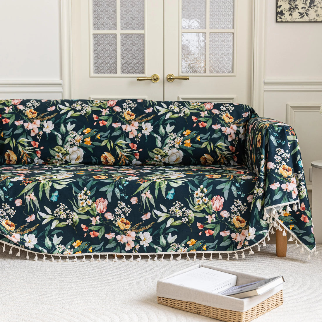 Elegant floral sofa cover with a dark navy background, featuring vibrant blossoms and green foliage, accented with white tassel trim.