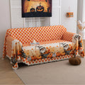 Autumn-themed sofa cover with an orange and white checkerboard pattern on the backrest and whimsical gnome illustrations on the seat, surrounded by pumpkins, leaves, and wheelbarrows, creating a cozy seasonal look.