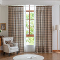 The curtains are made of a sheer, lightweight fabric with a semi-transparent quality that allows natural light to filter through. Their design features a plaid pattern in warm brown, beige, and subtle gray tones, giving them a cozy yet airy appearance.