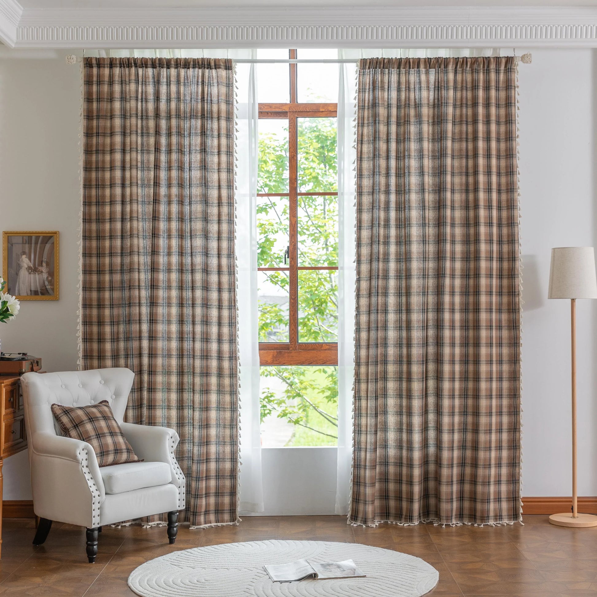The curtains are made of a sheer, lightweight fabric with a semi-transparent quality that allows natural light to filter through. Their design features a plaid pattern in warm brown, beige, and subtle gray tones, giving them a cozy yet airy appearance.