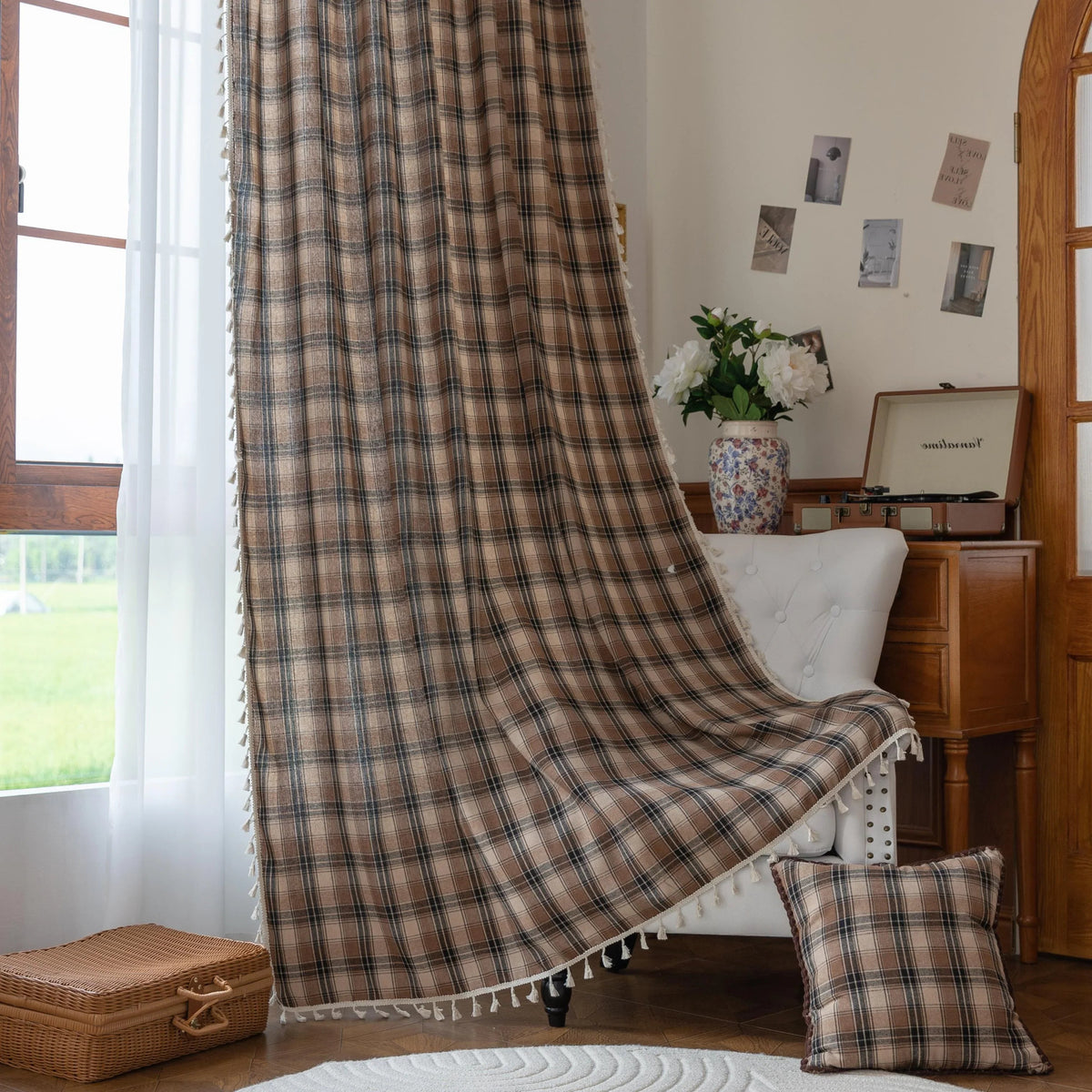 Brown, beige, and black plaid curtain fabric with a soft, textured weave and decorative white tassel trim along the edge.