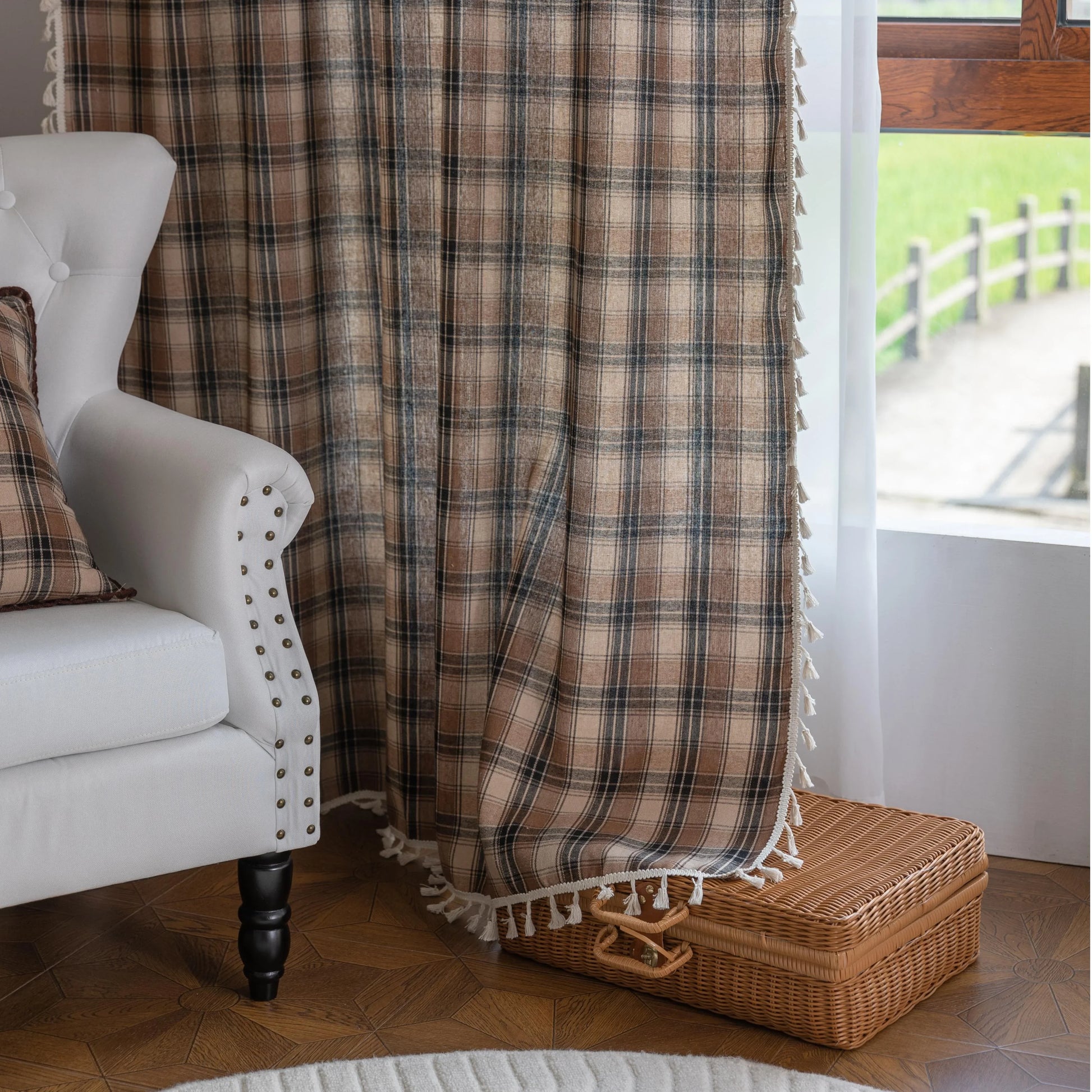 Brown, beige, and black plaid curtain fabric with a soft, textured weave and decorative white tassel trim along the edge.