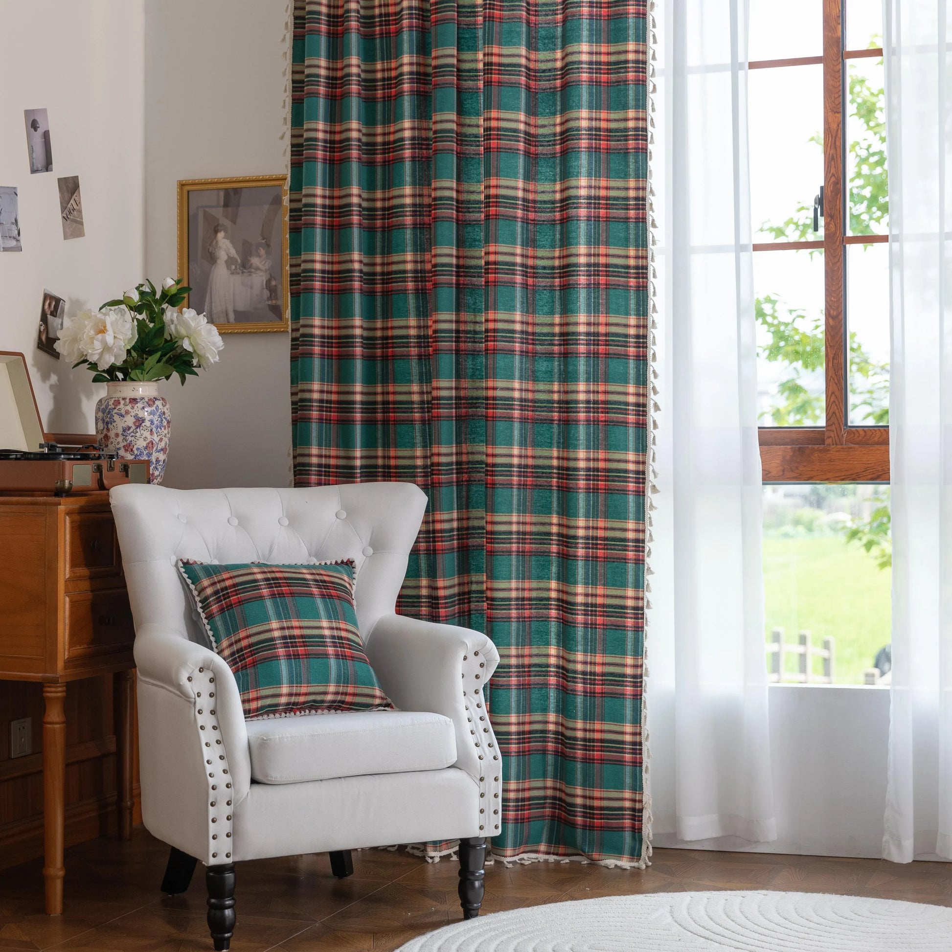 Green, red, and beige plaid curtain fabric with a soft, woven texture, finished with decorative white tassel trim along the edge.