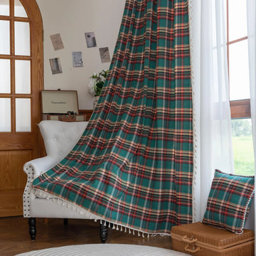 Green, red, and beige plaid curtain fabric with a soft, woven texture, finished with decorative white tassel trim along the edge.