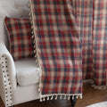 Red, navy blue, and beige plaid curtain fabric with a soft, textured weave and decorative white tassel trim on the edge.