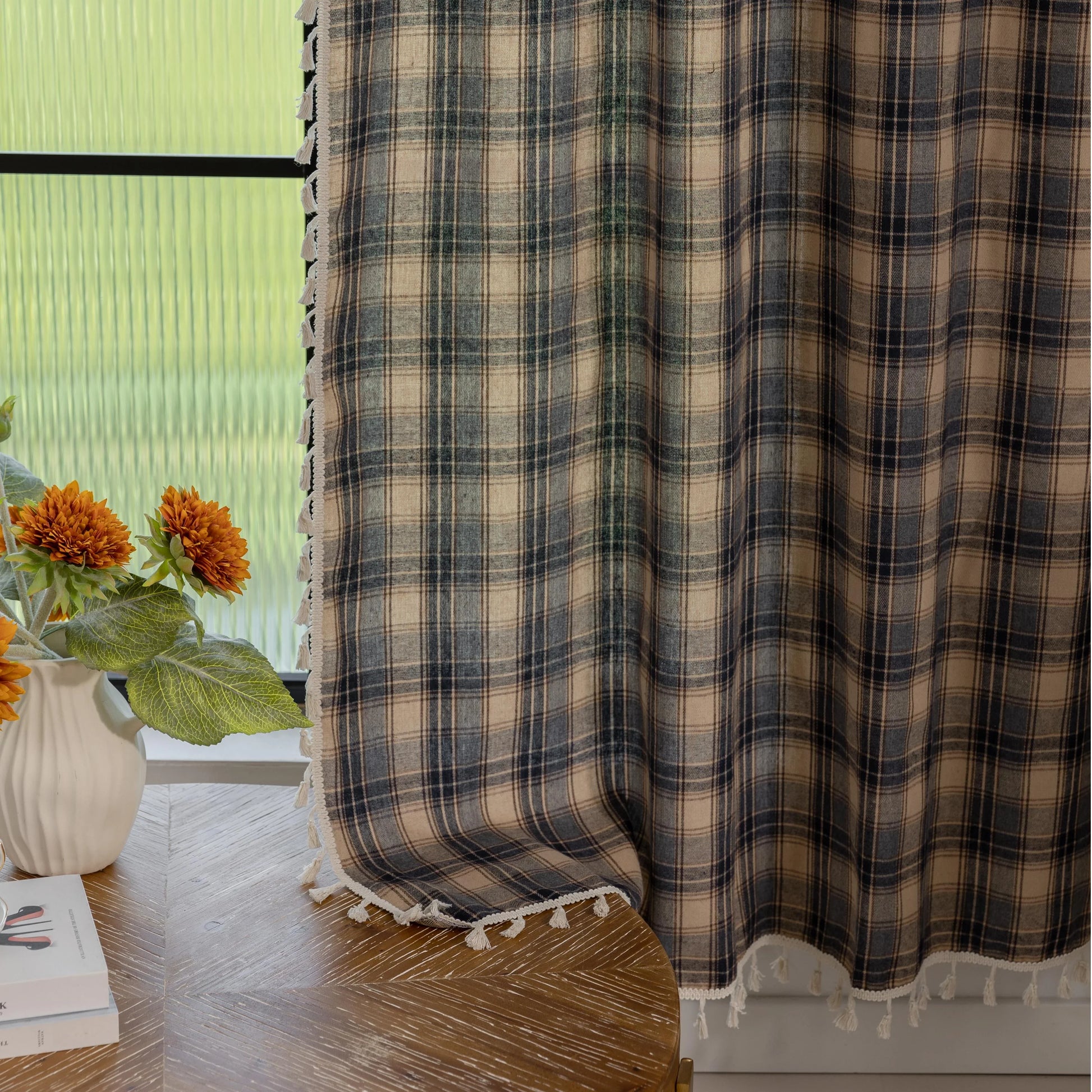 Beige and navy blue plaid curtain fabric with a soft, textured weave and decorative white tassel trim along the edge.