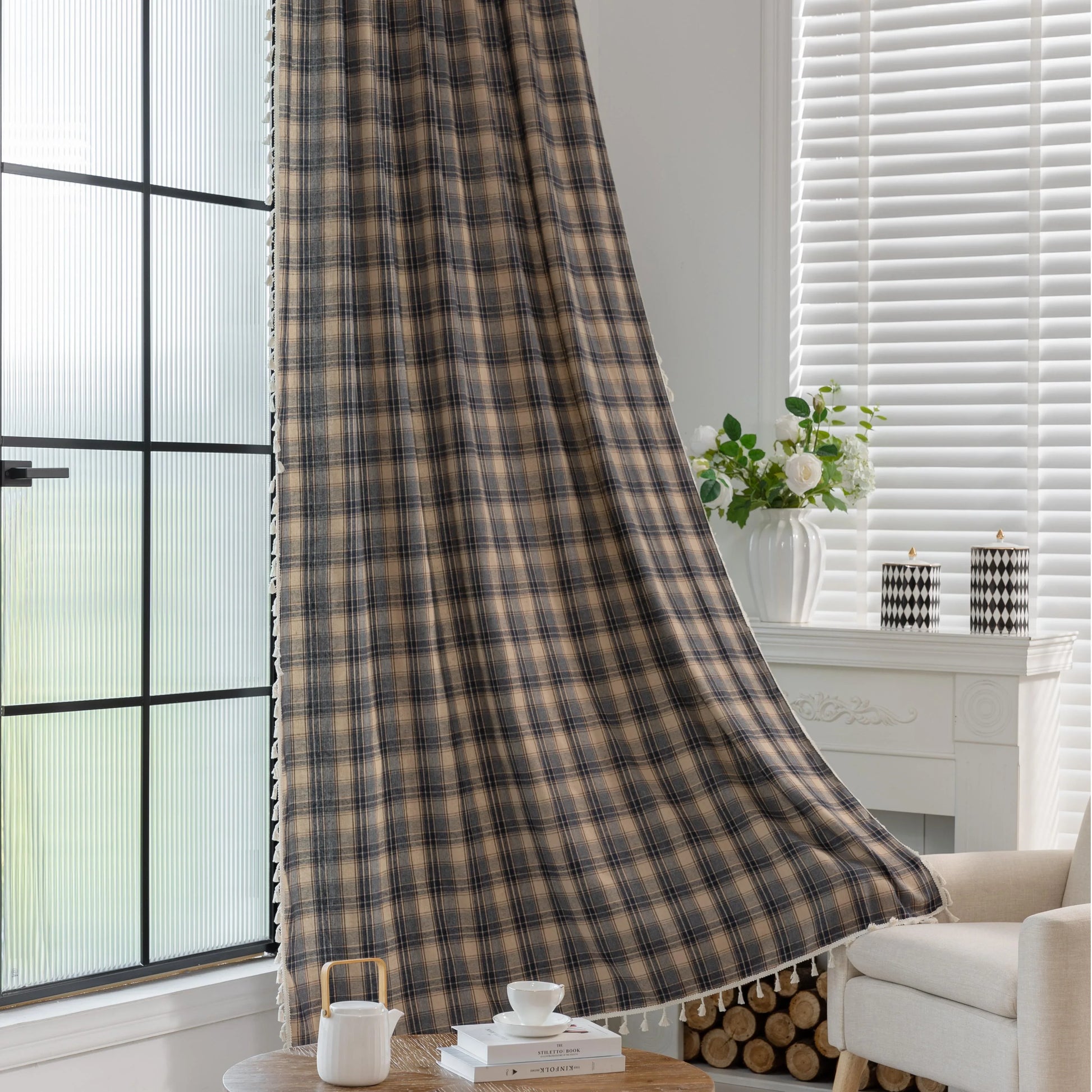 Beige and navy blue plaid curtain fabric with a soft, textured weave and decorative white tassel trim along the edge.