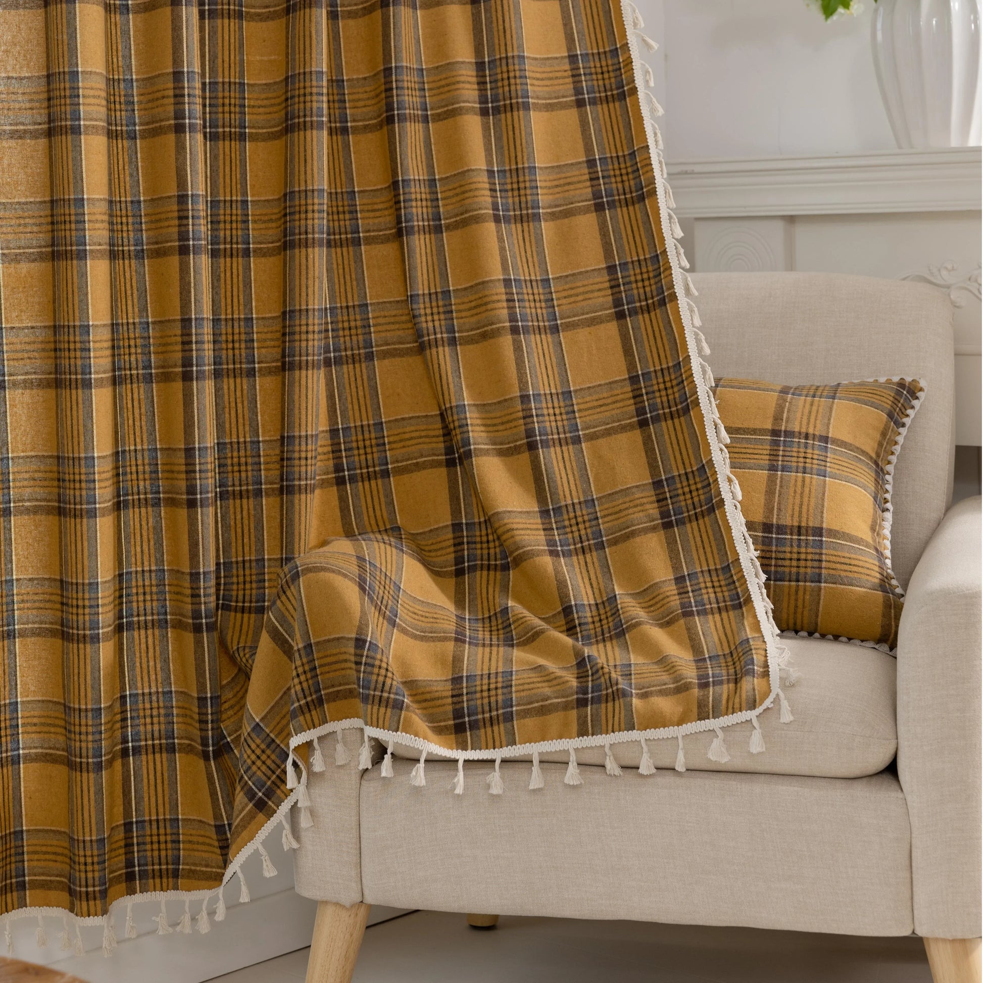 Mustard yellow and navy blue plaid curtain fabric with a soft, woven texture and decorative white tassel trim on the edge.