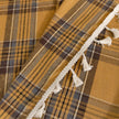 Mustard yellow and navy blue plaid curtain fabric with a soft, woven texture and decorative white tassel trim on the edge.