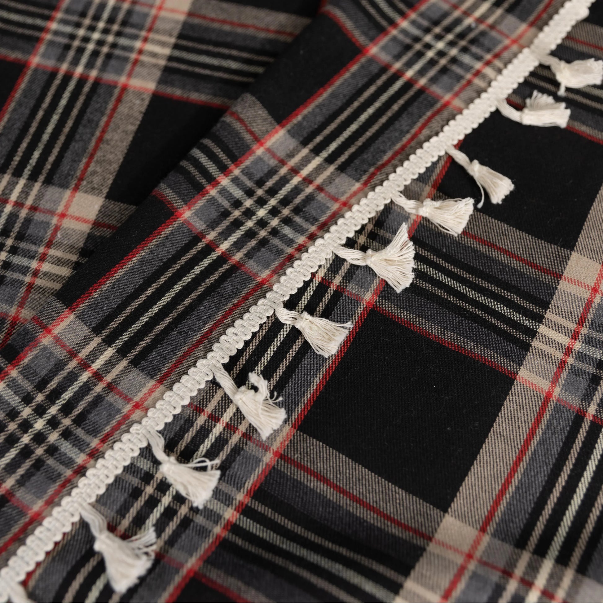 Elegant black plaid curtain fabric featuring intersecting thin white and subtle red lines, creating a classic tartan pattern.