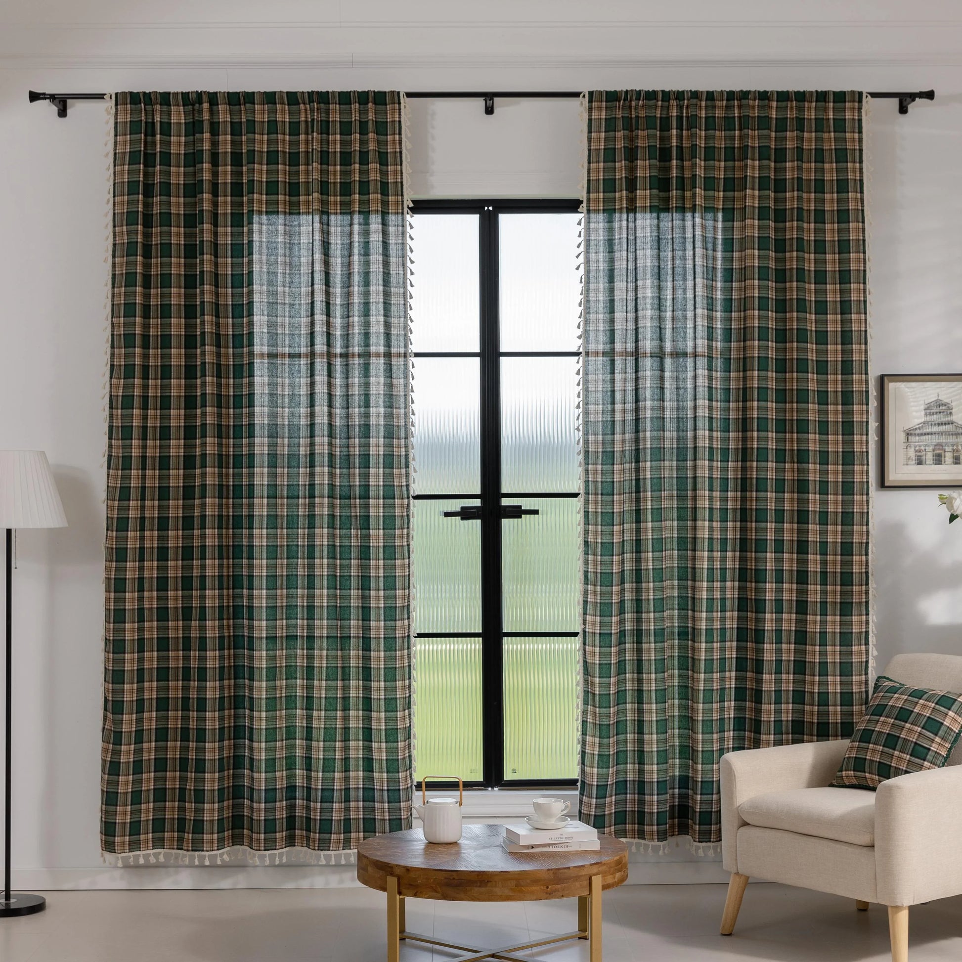 Green and beige plaid curtain fabric with a soft, woven texture, accented by decorative white tassel trim along the edge.