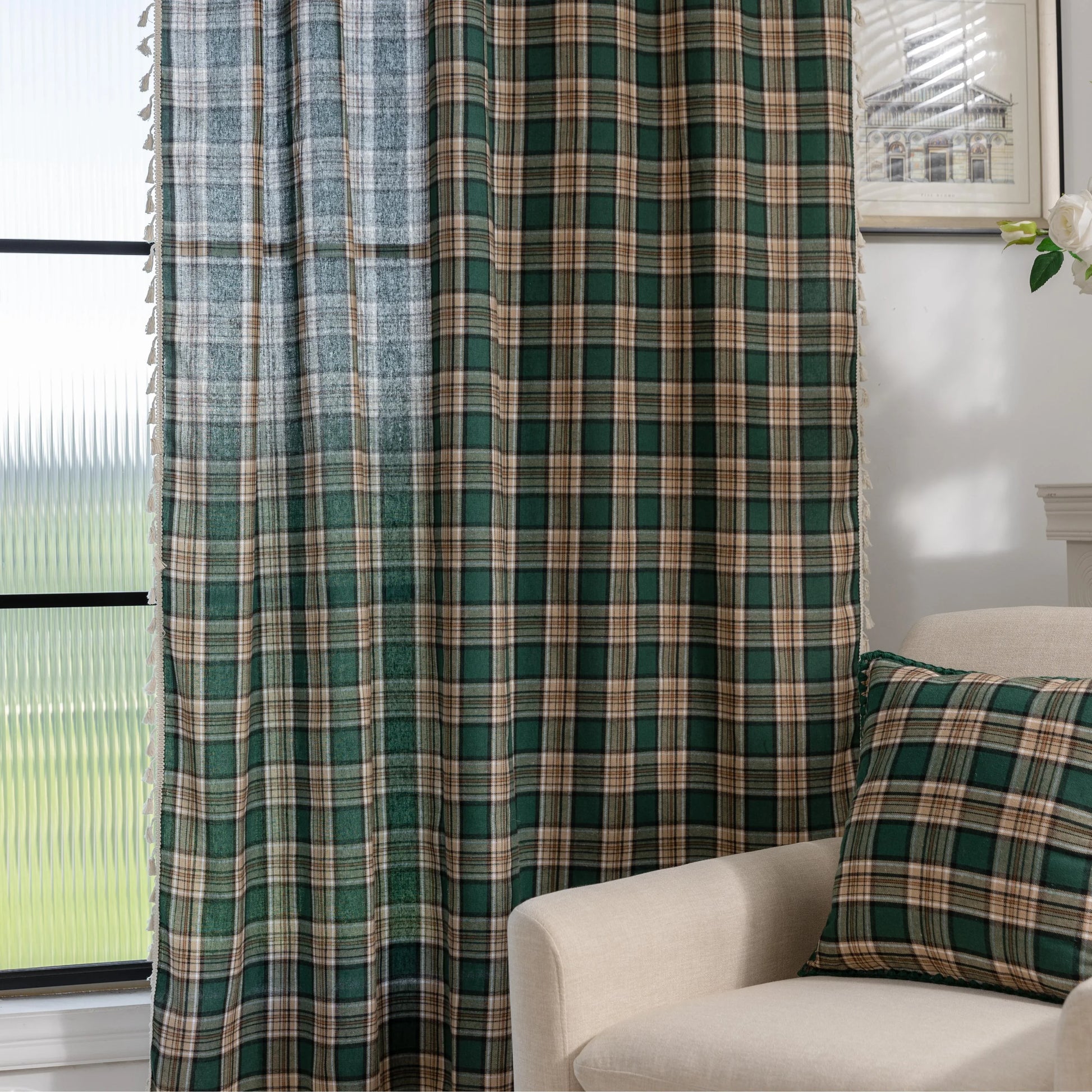 Green and beige plaid curtain fabric with a soft, woven texture, accented by decorative white tassel trim along the edge.