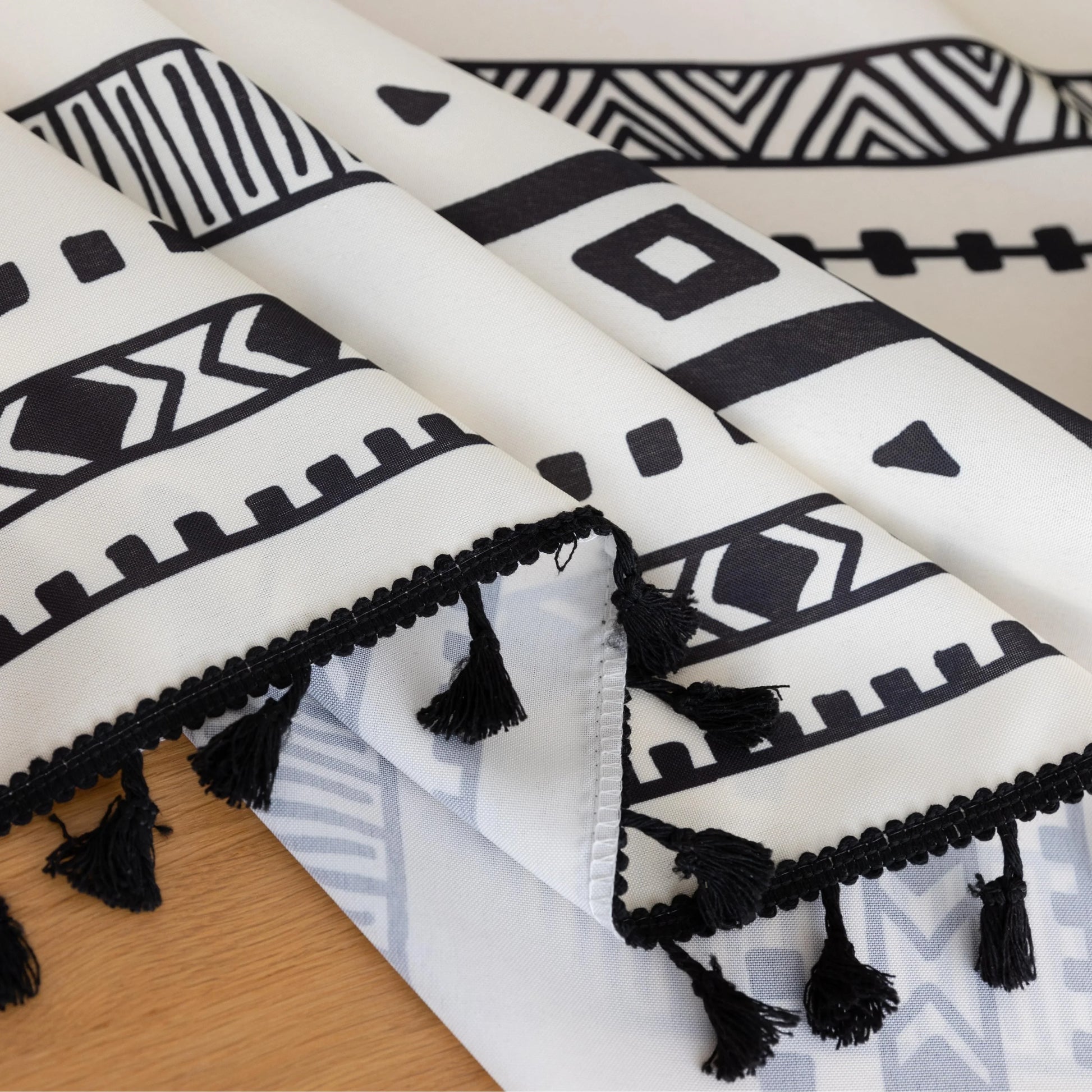 Modern black and white geometric patterned tablecloth with tribal-inspired diamond and stripe designs.